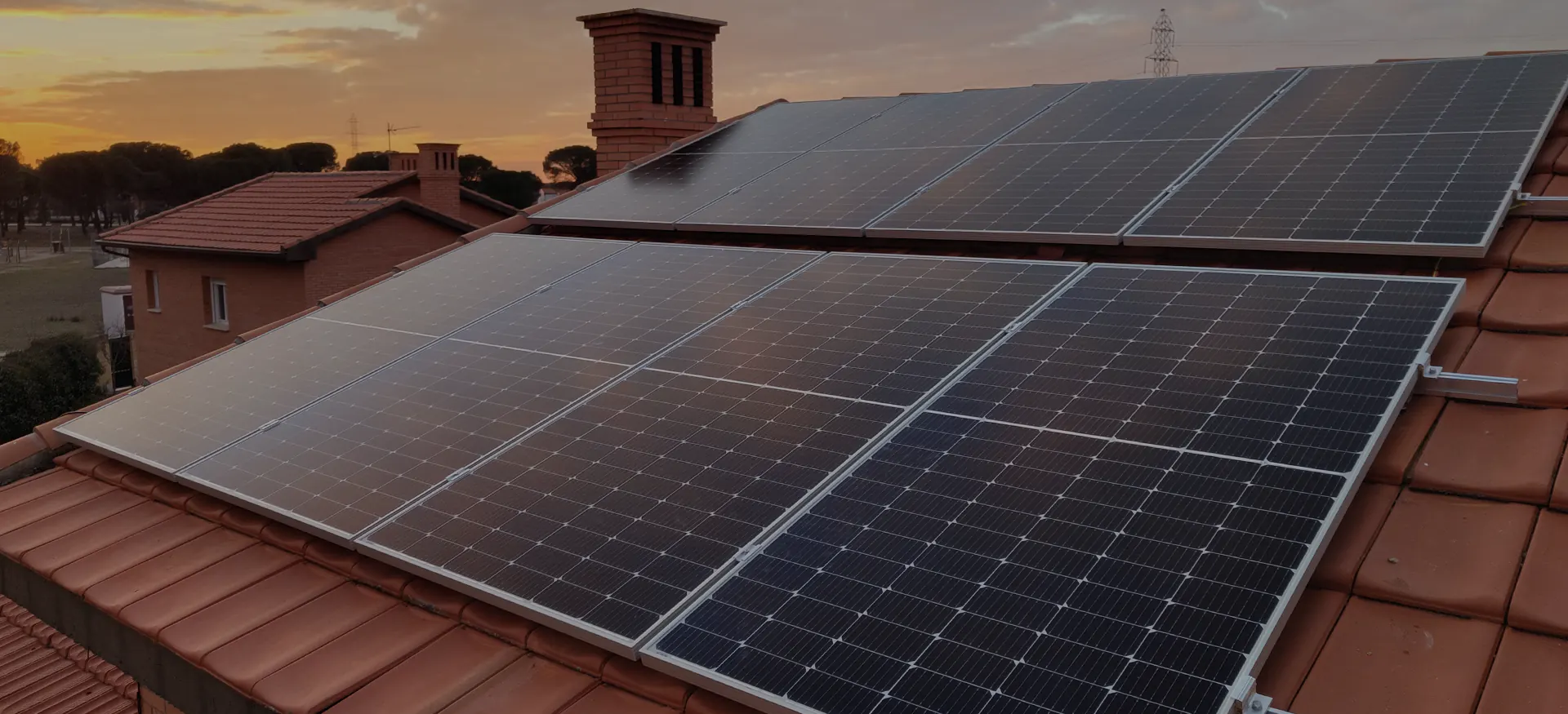placas solares sobre tejado naranja con chimenea y atardecer